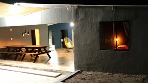 A dining area with a wooden table and chairs, a yellow chair, and a window with a lit interior. - Casa de Playa con Mini Golf (La Libertad Department)