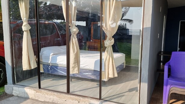 A room with a bed, curtains, a purple chair, and a wooden table. - Casa de Playa con Mini Golf (La Libertad Department)