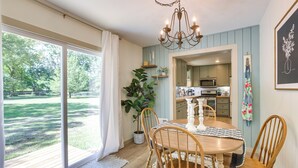 A dining area with a wooden table and chairs, a chandelier, and a view of the outdoors. - Pet-Friendly Alabama Retreat w/ Deck & Patio! (Moody)