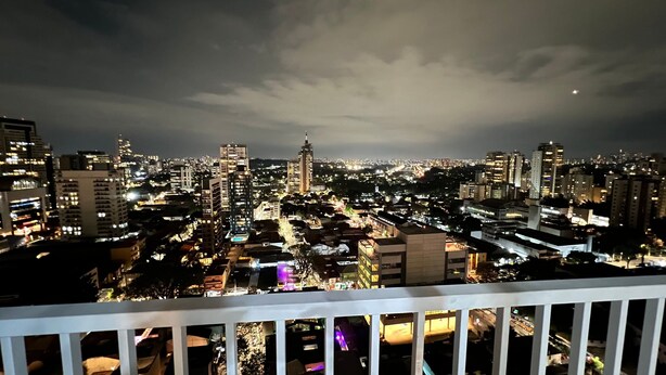 A nighttime cityscape with illuminated buildings and a cloudy sky. - MichiH - Perfeito Studio em Pinheiros (São Paulo)