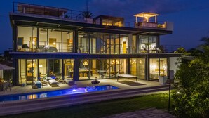 A modern two-story house with a swimming pool, outdoor seating, and a covered patio. - Casa Balam: Private Chef Included - Waterfront Villa - 40ft Pool - Sunset Views (Placencia)
