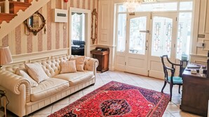 A room with a staircase, a sofa, a rug, and a door with an 'EXIT' sign. - Herbert House (Killarney)