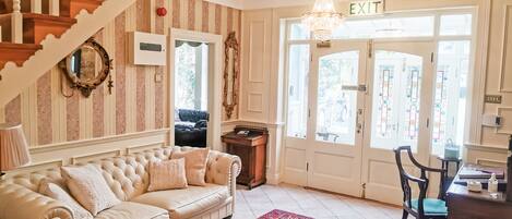 A room with a staircase, a sofa, a rug, and a door with an 'EXIT' sign.