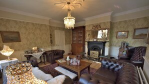 A traditional living room with a fireplace, leather sofas, a chandelier, and a patterned carpet. - Herbert House (Killarney)