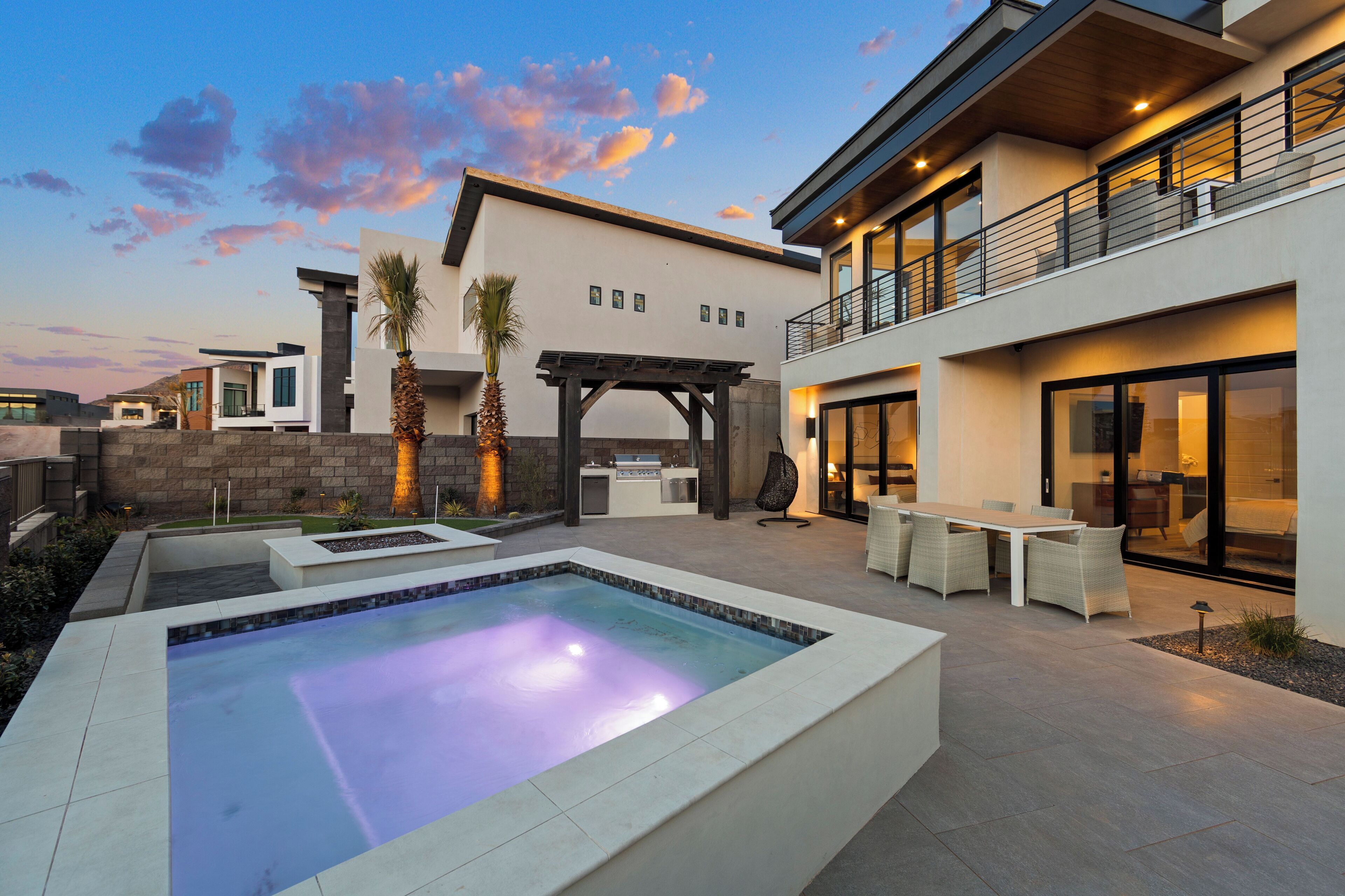 A modern outdoor living area with a pool, patio furniture, and a covered barbecue area.