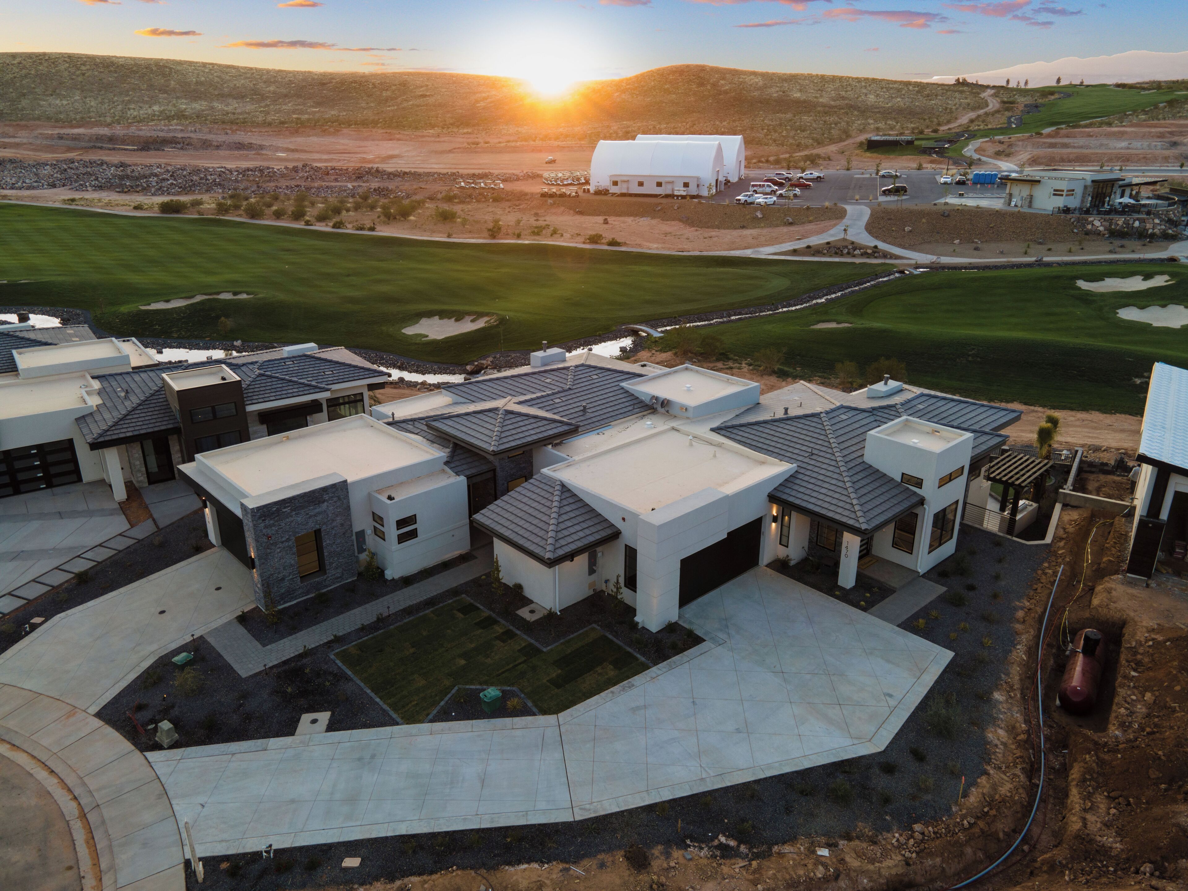 Un desarrollo residencial moderno con varias casas de techos planos y un edificio comunitario central.