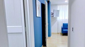 Un pasillo con una pared azul, una puerta blanca y una silla azul al fondo.