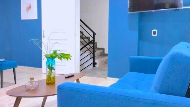 Una sala de estar con un sofá azul, una mesa de centro y un televisor montado en la pared.