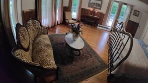 Un salon chaleureux avec un canapé à motifs, une table basse agrémentée de fleurs, un piano et un escalier.