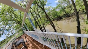 Une terrasse en bois avec une balustrade blanche donnant sur une rivière.