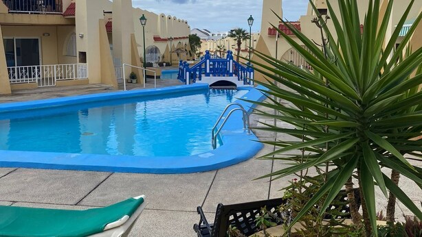 A swimming pool with a blue deck, a bridge, and a palm tree. - Mare Verde A10 (Costa Adeje)