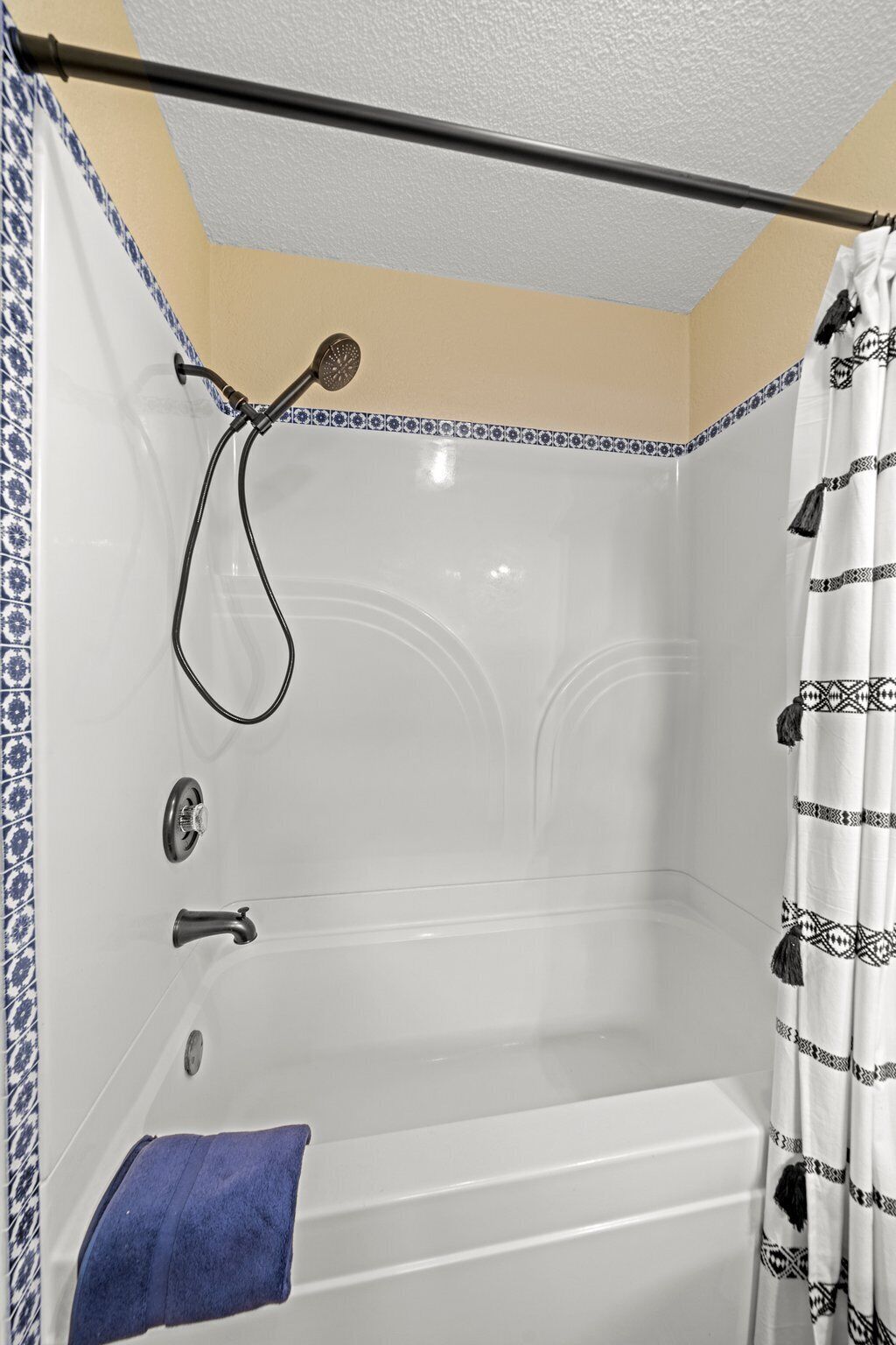A bathroom with a bathtub, showerhead, and a towel rack.