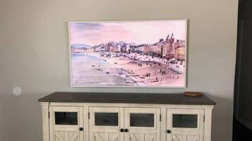 Un tableau représentant une ville côtière, avec des bâtiments et une plage.