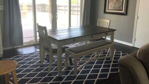 A dining area with a dark wooden table, two chairs, a bench, and a patterned rug. - Casa Padre, Perfect for long term stays. (Weslaco)