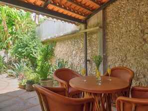 A covered outdoor seating area with a stone wall and potted plants. - Cozy house & secret garden with pool in Centro (Centro)