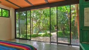 A bedroom with a large sliding glass door leading to a garden. - Cozy house & secret garden with pool in Centro (Centro)