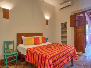 Une chambre à coucher avec un lit en bois, une chaise verte et une étagère.