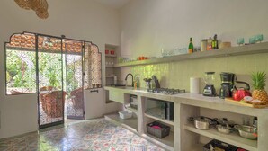 A kitchen with a tiled floor, a gas stove, a sink, and various kitchen utensils. - Cozy house & secret garden with pool in Centro (Centro)