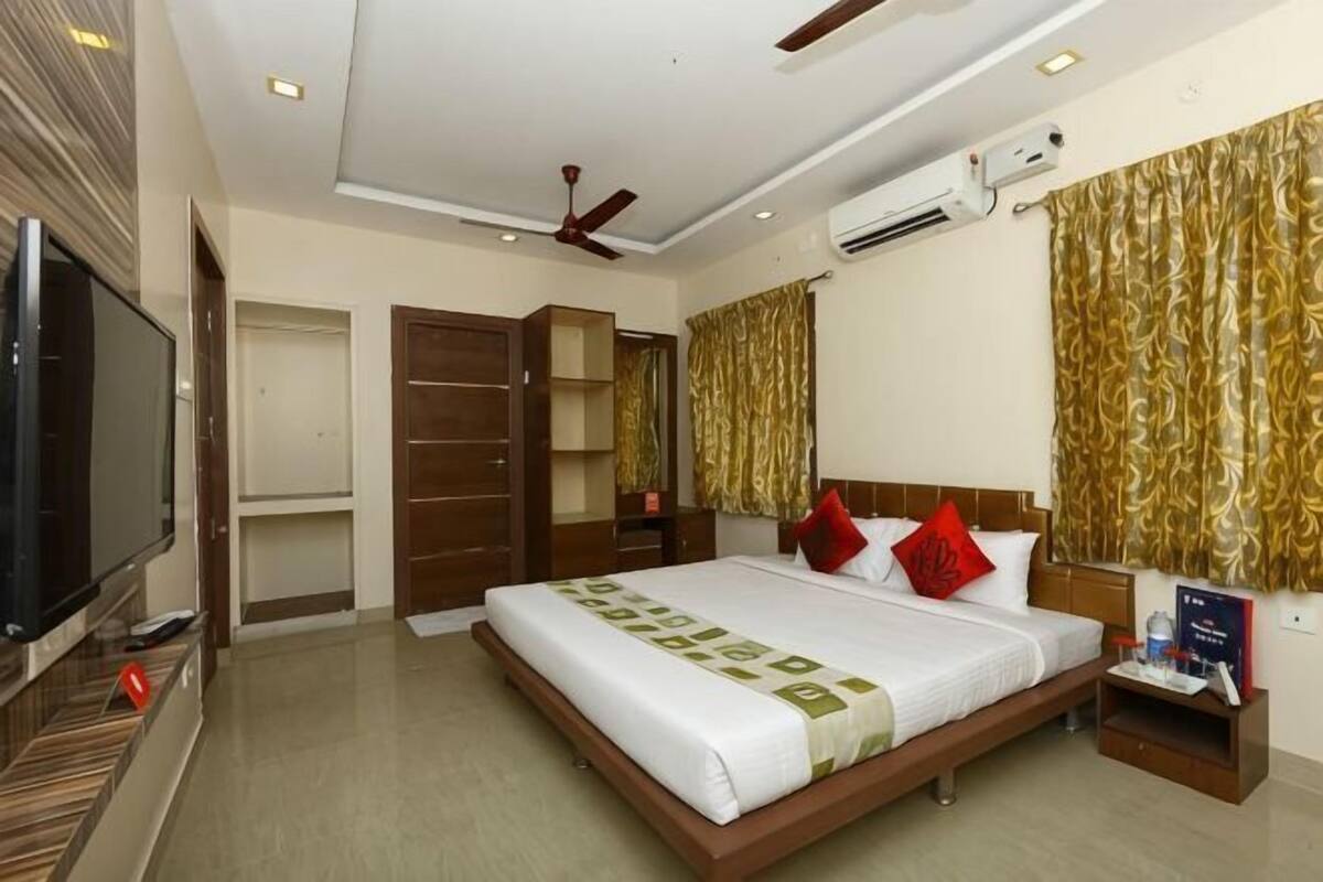 Une chambre d’hôtel équipée d’un lit, d’une télévision, d’une armoire et d’un ventilateur de plafond.
