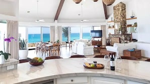 A spacious kitchen with white cabinetry, a large island, and a view of the ocean. - Luxury Beachfront Gem ~ Panoramic Sea Views ~ Heated Pool (B.C.S.)