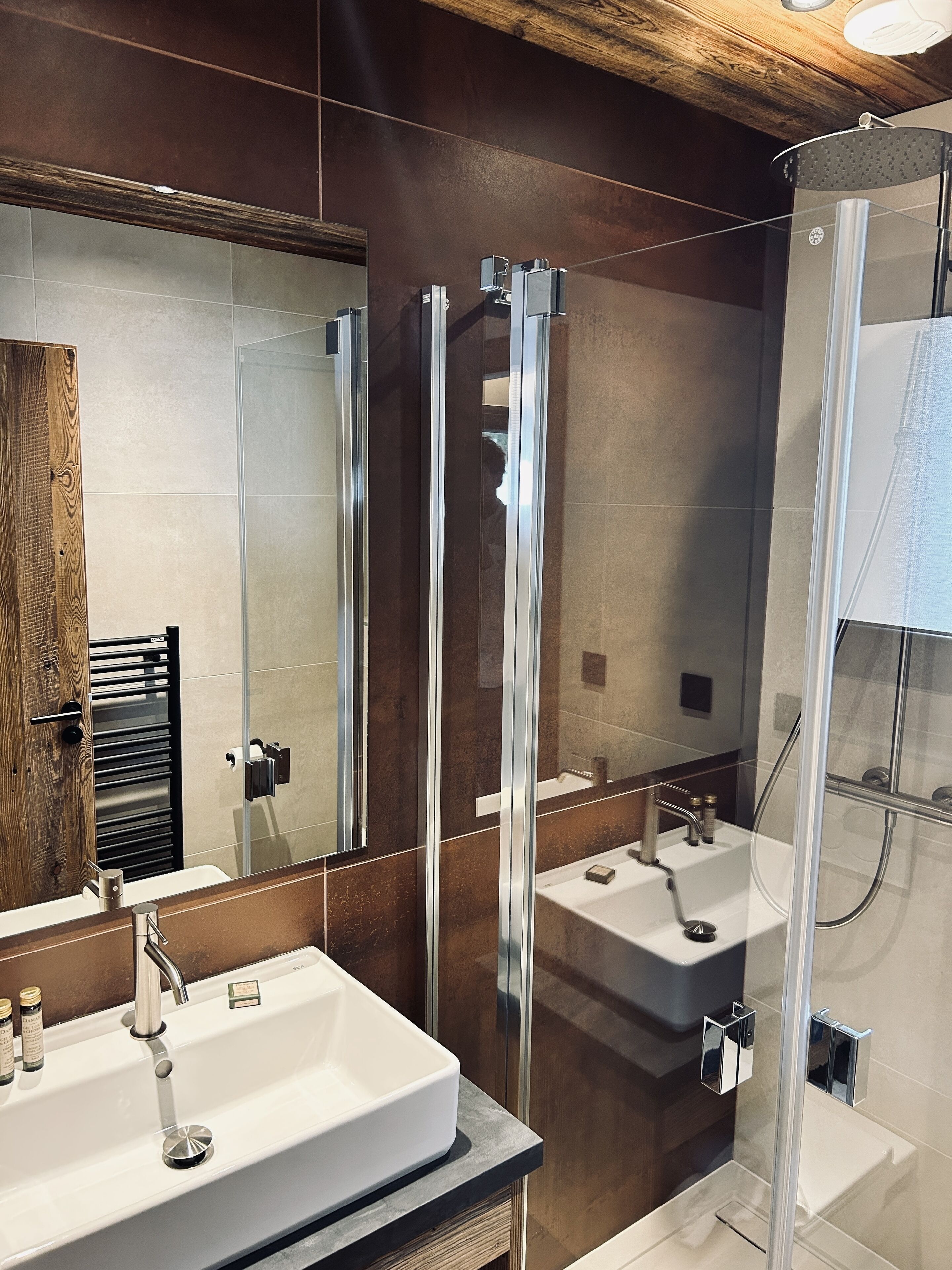 A modern bathroom with a large mirror, two sinks, and a glass-enclosed shower.