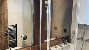 A modern bathroom with a large mirror, two sinks, and a glass-enclosed shower.