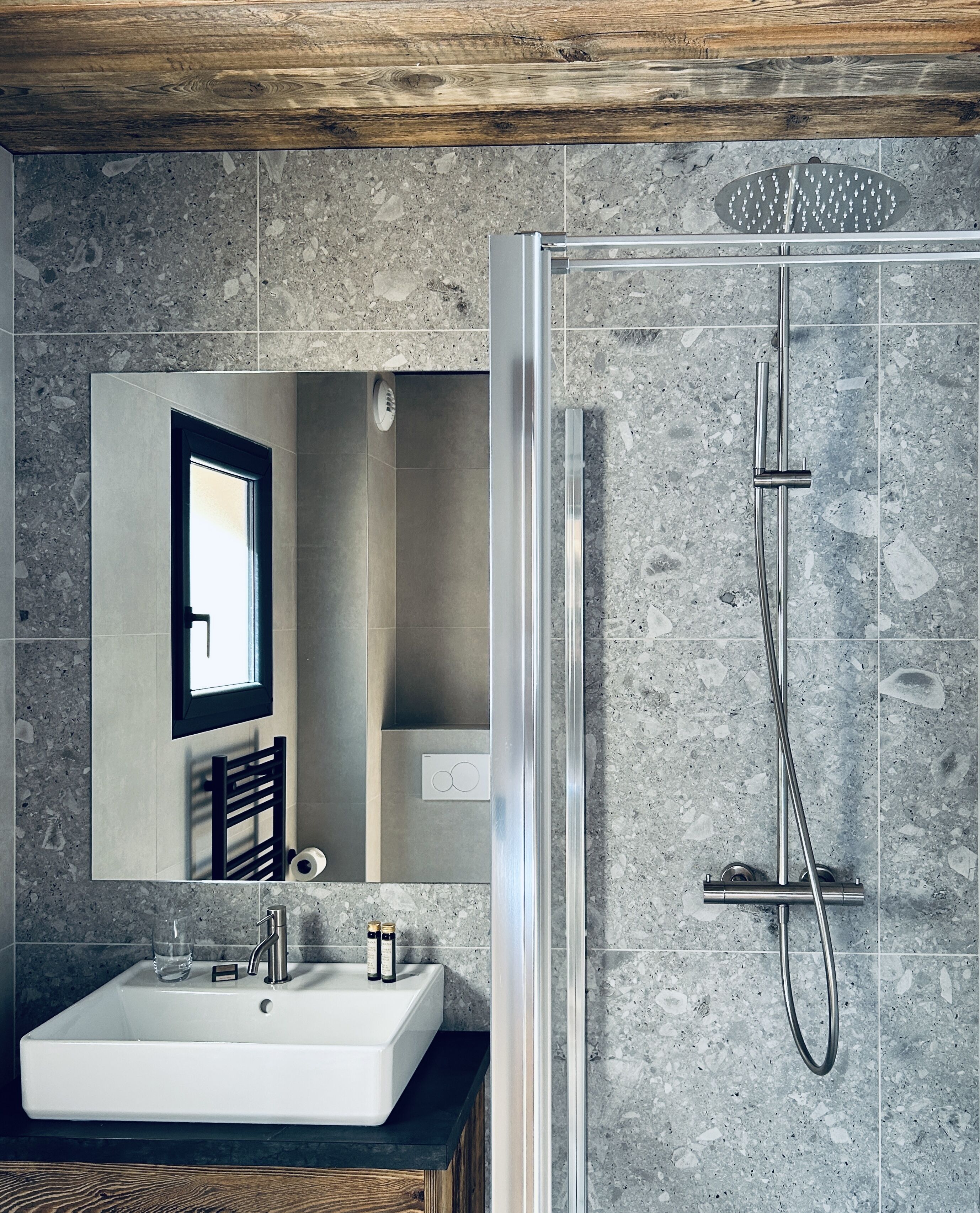 A modern bathroom with a rectangular sink, a mirror, and a shower with a handheld showerhead.