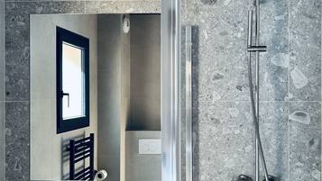 A modern bathroom with a rectangular sink, a mirror, and a shower with a handheld showerhead.