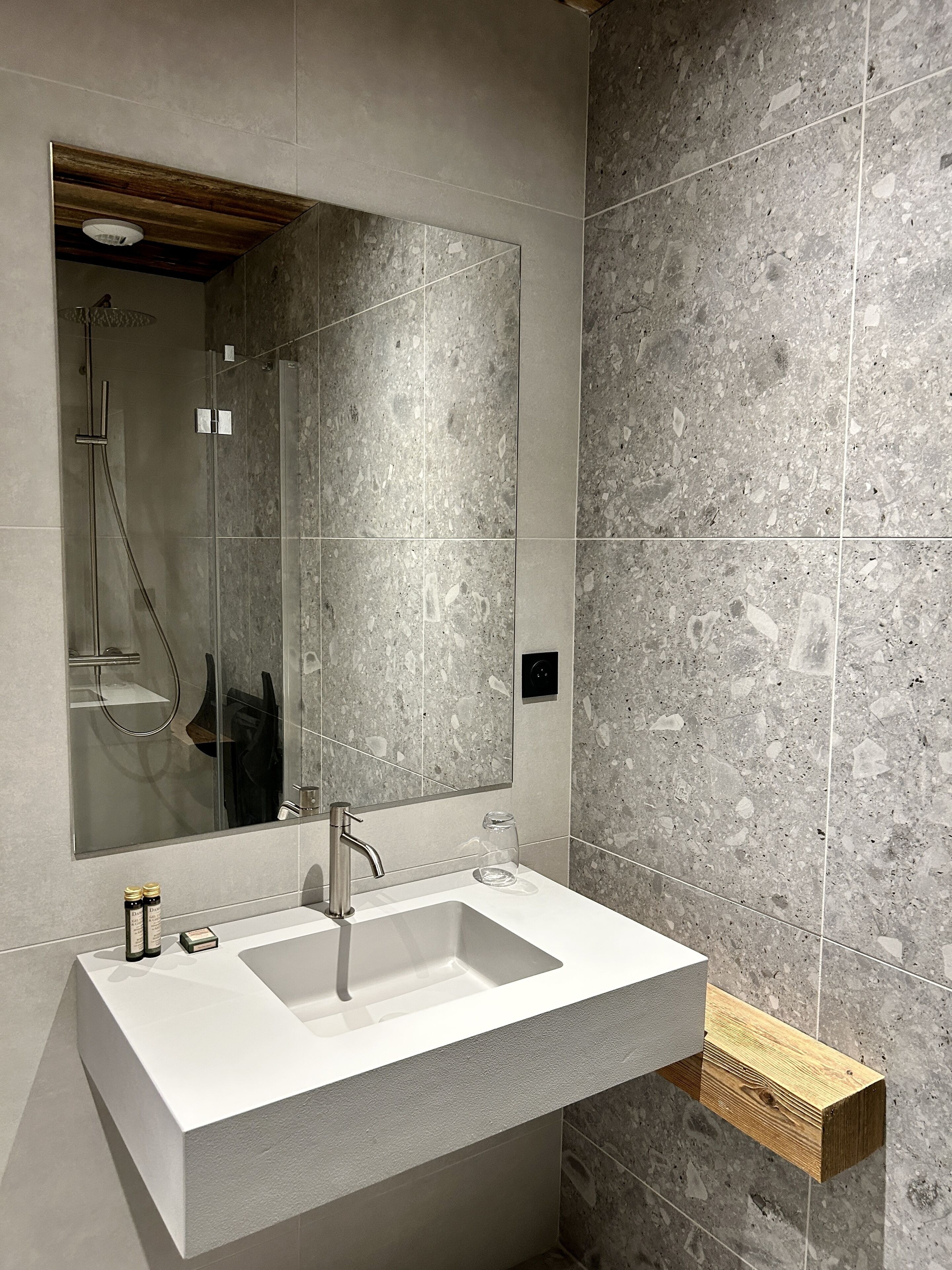 Une salle de bain moderne avec un grand miroir, un lavabo blanc et un espace douche.
