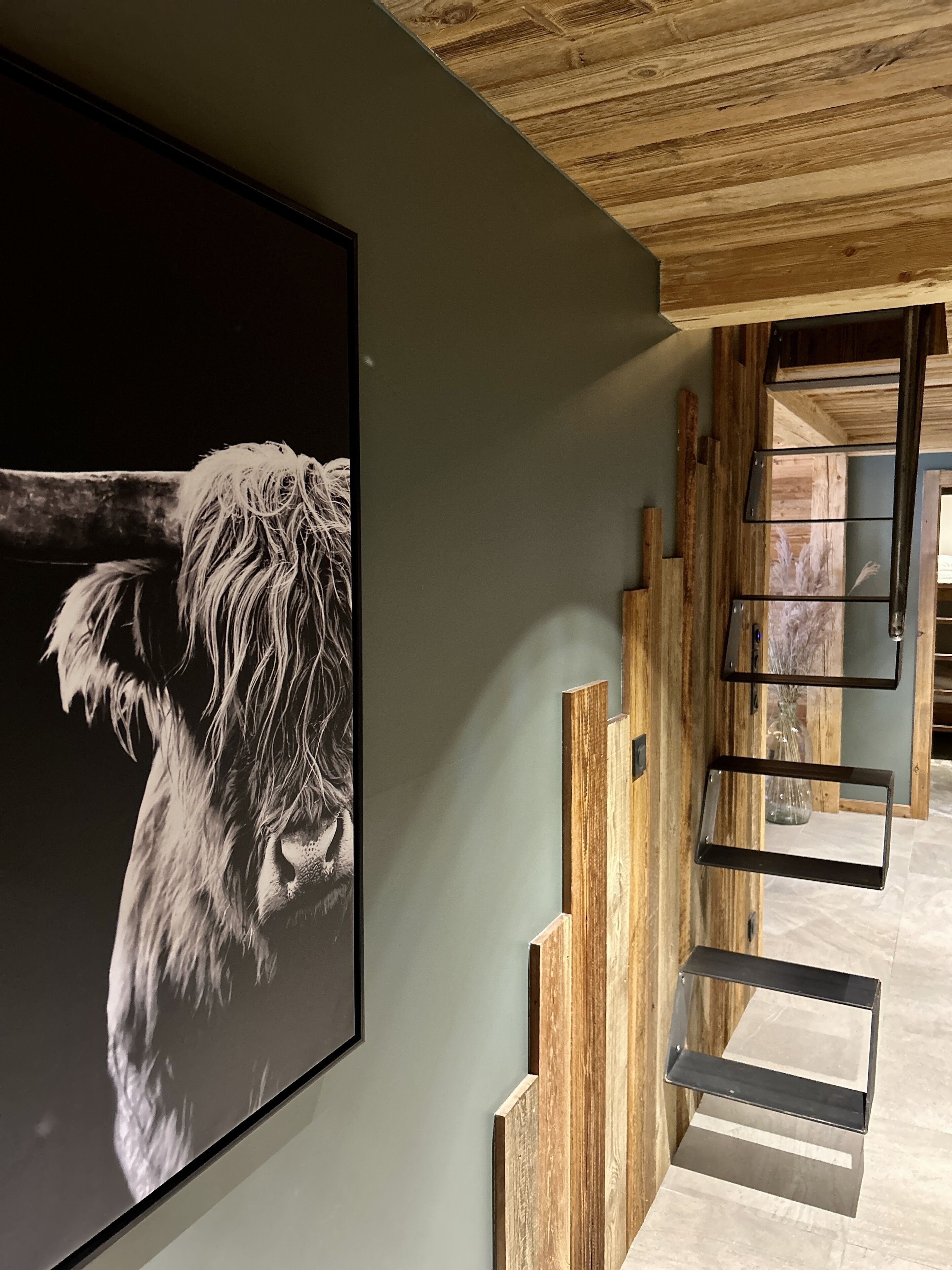 A modern interior with a framed photograph of a dog, wooden wall accents, and a metal shelf unit.