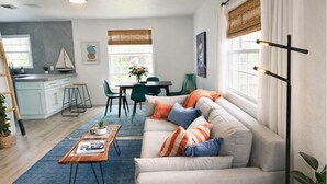 A modern living room with a sofa, coffee table, and dining area. - Naples Art District (Naples)