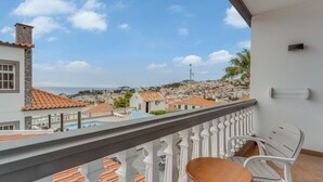 A balcony with a white railing, a wooden table, and white plastic chairs. - Villa Winter Apt. 2 (Funchal)