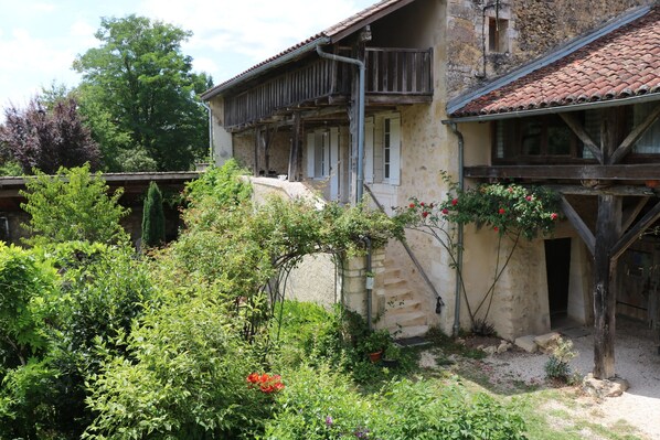 A rustic building with a balcony and a garden area.