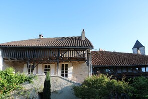 A traditional half-timbered house with a steeply pitched roof, stone walls, and a visible chimney.