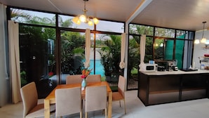 A modern kitchen with a dining area, large windows, and a view of a pool. - Hotel Ballena REY (Bahía Ballena)