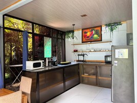 Una cocina moderna con un amplio ventanal, microondas, cafetera y refrigerador.