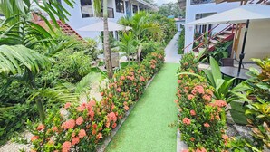 A garden pathway with artificial grass, surrounded by lush greenery and flowering plants. - Hotel Ballena REY (Bahía Ballena)