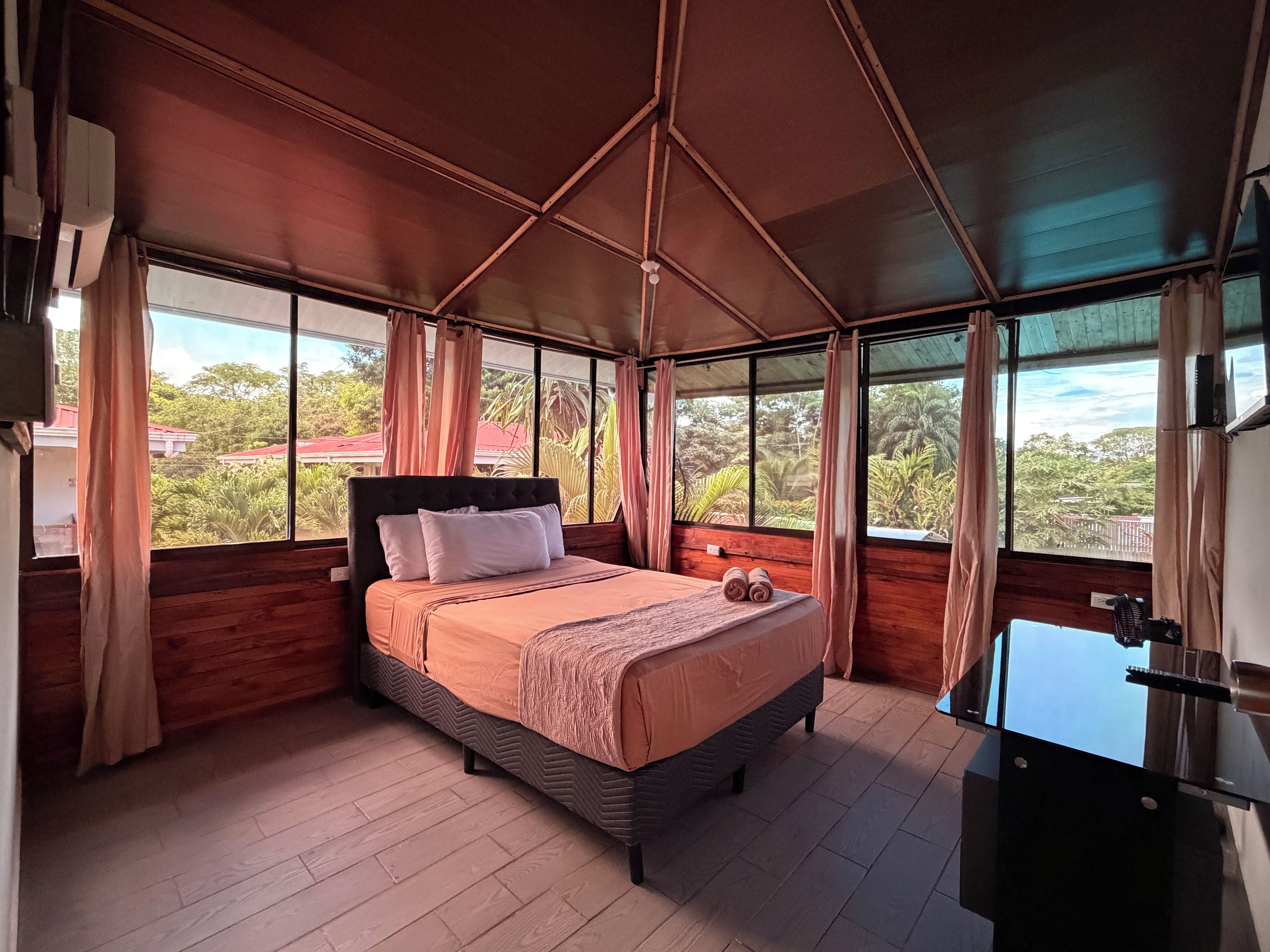 A bedroom with a bed, curtains, and a view of greenery outside.