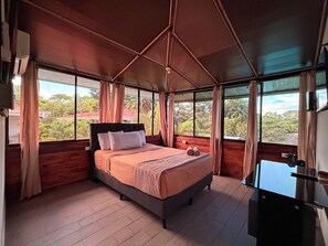 A bedroom with a bed, curtains, and a view of greenery outside. - Hotel Ballena REY (Bahía Ballena)
