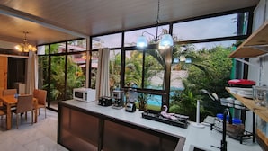 A modern kitchen with a large window, wooden furniture, and various appliances. - Hotel Ballena REY (Bahía Ballena)