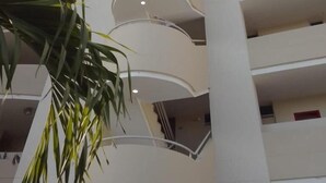 A multi-story building with a modern architectural design, featuring balconies and a central stairwell.
