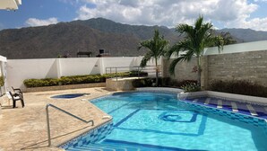 A swimming pool with a stone deck and a view of mountains in the background.