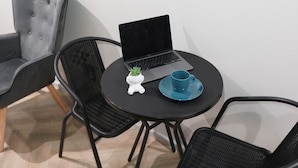Ett litet rum med ett runt bord, två stolar, en bärbar dator, en blå kopp och en klocka på väggen.