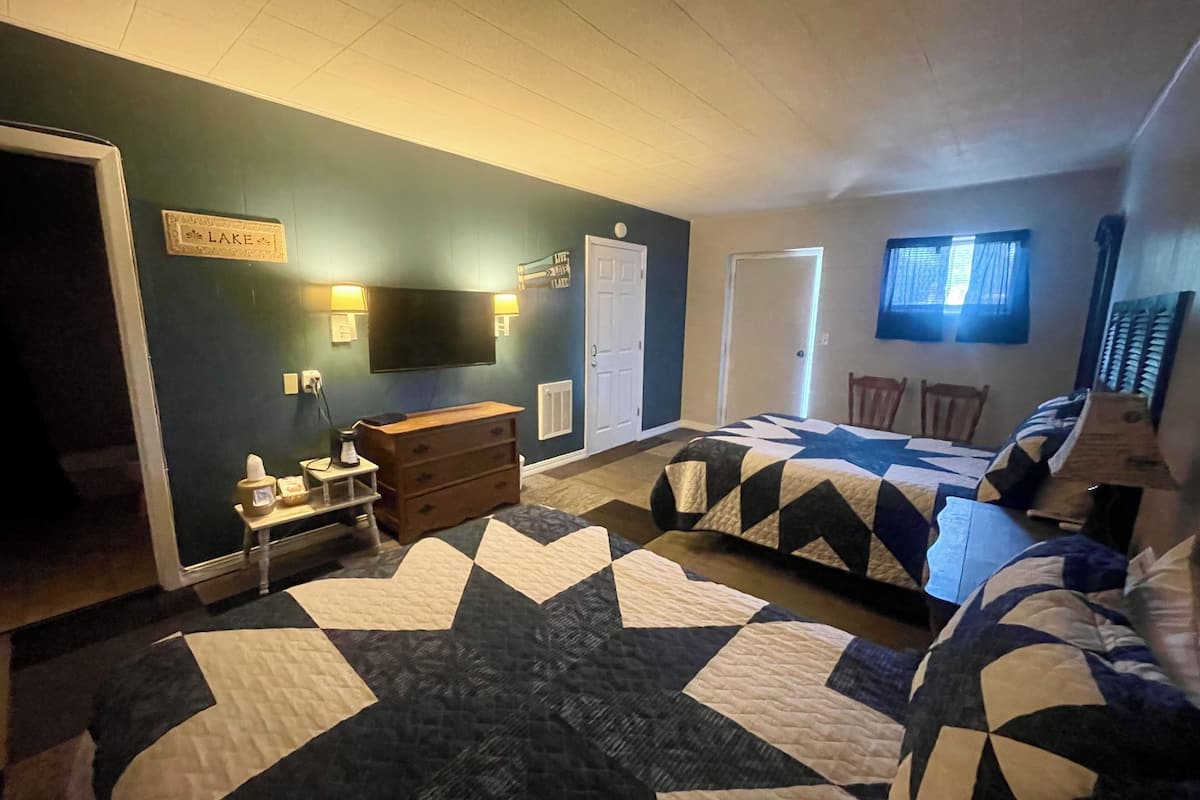 A bedroom with two beds, a dresser, a TV, and a sign on the wall.