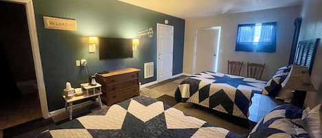 A bedroom with two beds, a dresser, a TV, and a sign on the wall.
