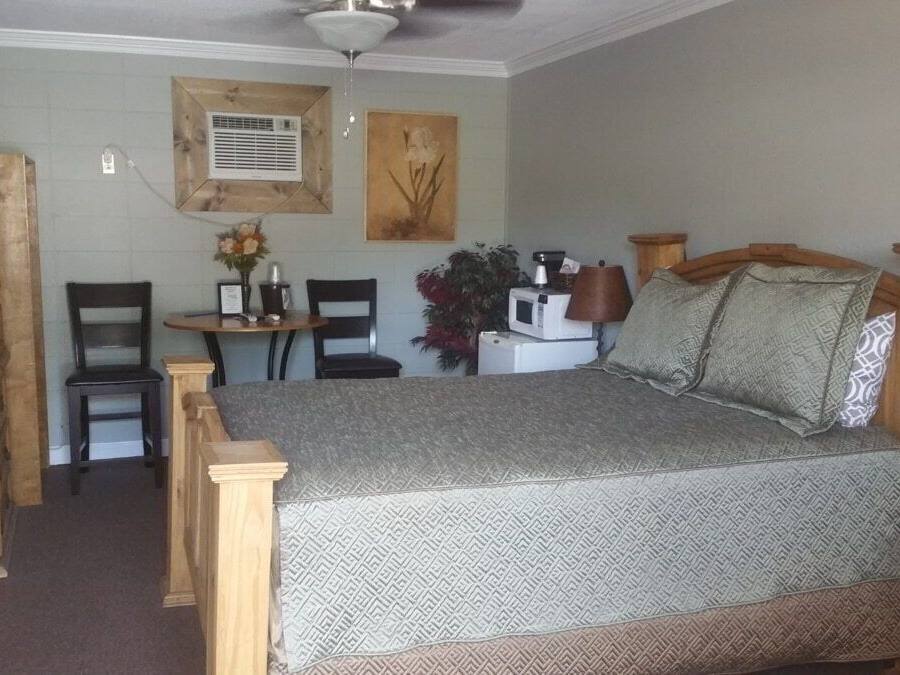 Un dormitorio con una cama, muebles de madera, un escritorio, sillas, un televisor y un aire acondicionado instalado en la pared.