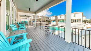A covered outdoor area with wooden flooring, blue Adirondack chairs, and a pool. - Steps To Beach & Lagoon, Overlooks Pool, Balcony Gulf Views, 4BR House, Sleep 12 (Gulf Shores)