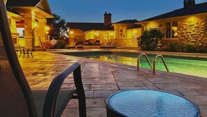 Zona junto a la piscina con muros de piedra, una piscina y sillas de descanso.
