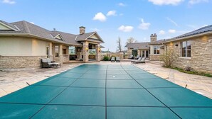 Un patio amplio con piscina, muros de piedra y zonas de estar al aire libre.