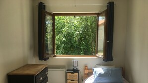 Une chambre avec une fenêtre, un lit, une commode et une table de chevet.